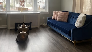 A living room with a blue sofa, a decorative vase, and a large window with a view of the outside. - COZY SUITE DREAM HOME IN BLOOMFIELD  (Bloomfield)