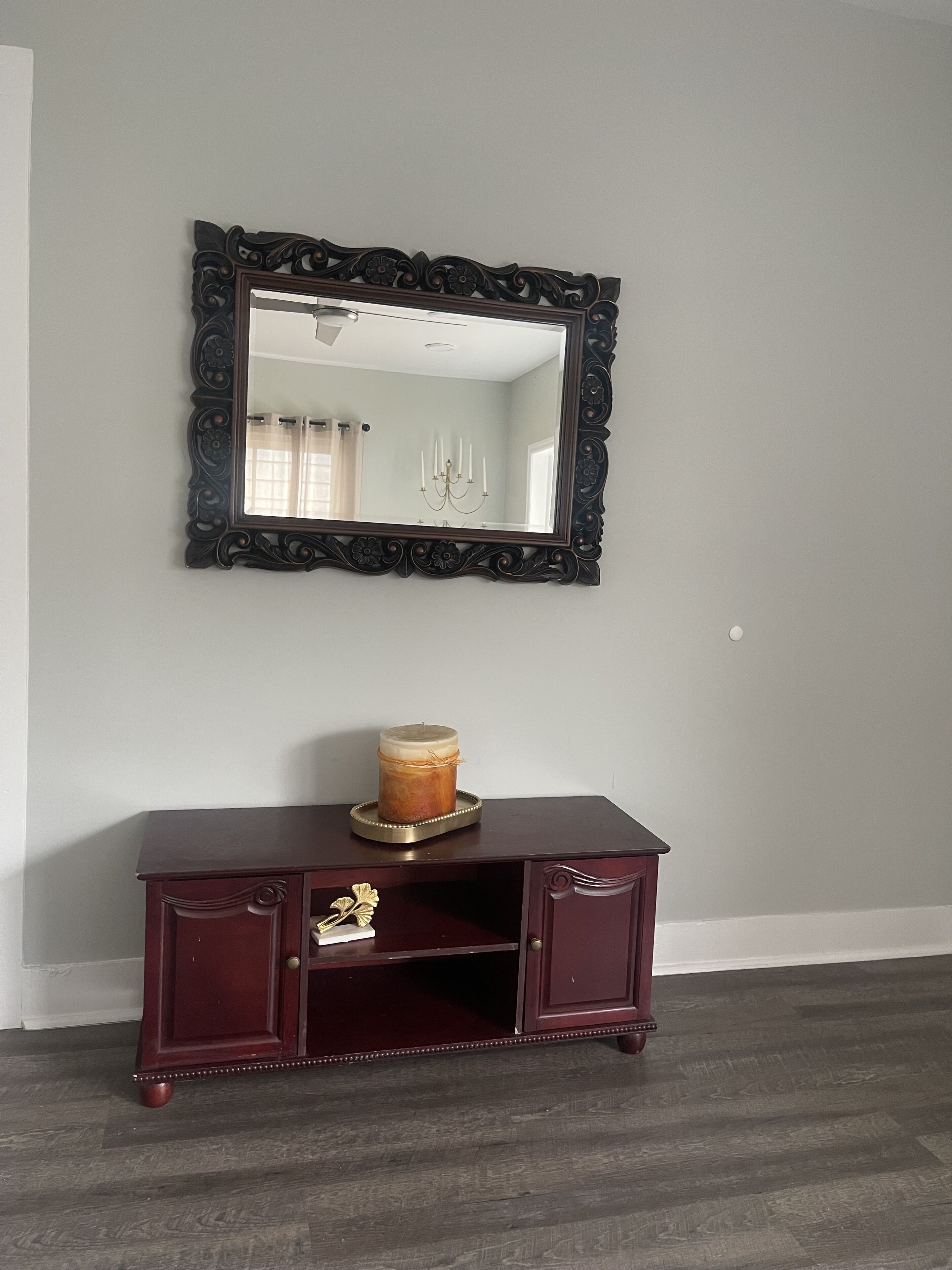 A dark wooden console table with a candle and a mirror above it.