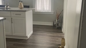 A kitchen with white cabinets, a granite countertop, a sink, and a window with sheer curtains. - COZY SUITE DREAM HOME IN BLOOMFIELD  (Bloomfield)