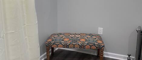 A bathroom with a bench, a mirror, and a radiator.