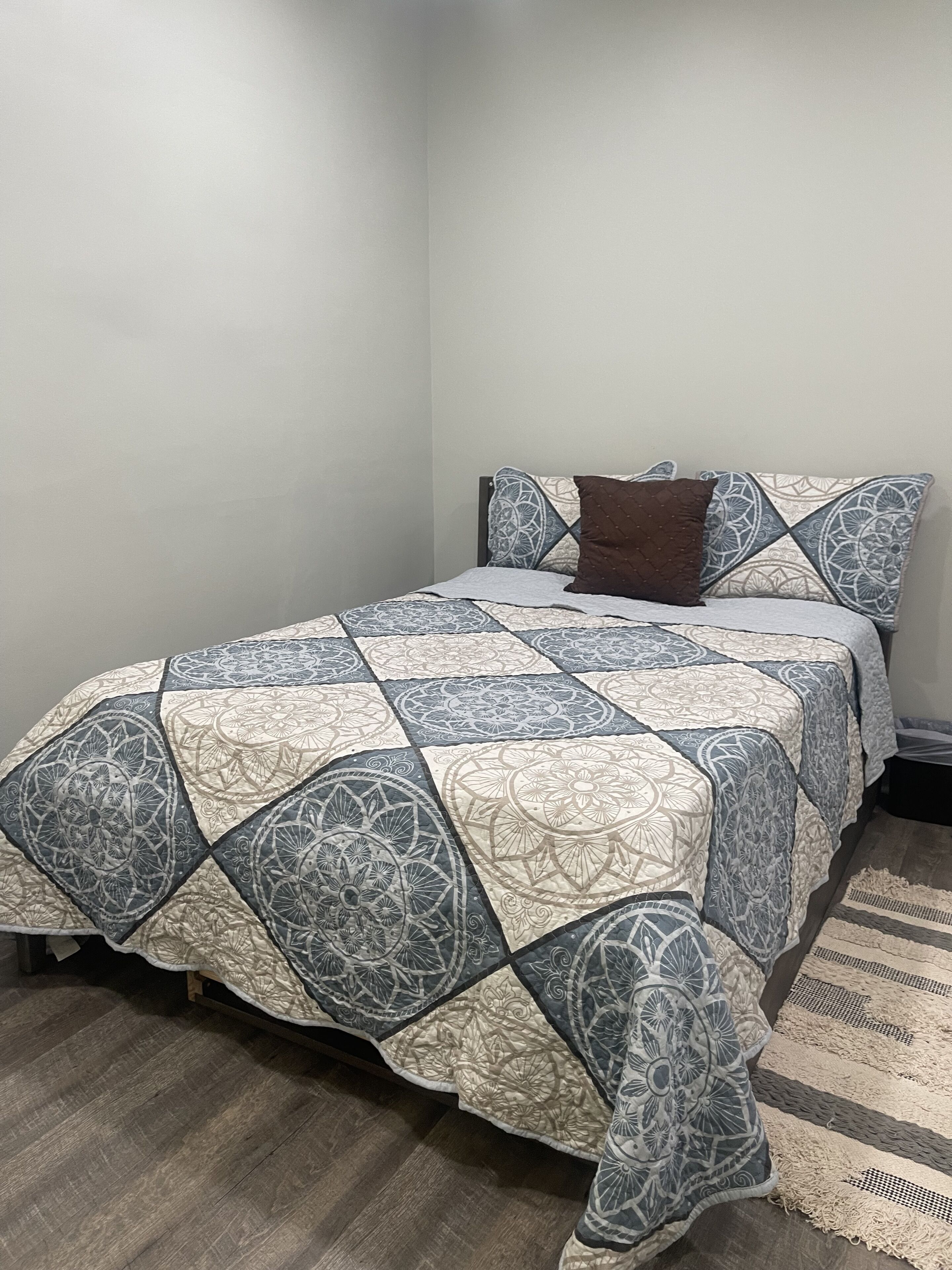 Una camera da letto con un letto coperto da una trapunta fantasia, un cuscino marrone e una coperta coordinata.
