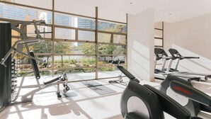 A gym with exercise equipment, large windows, and a view of the outdoors. - Boho Apartment - Pool, Parking & Mall. (Las Condes)