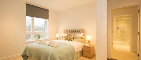 A bedroom with a bed, nightstands, a window with a view, and a door leading to another room.