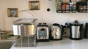 A kitchen with a toaster, kettle, and colander on the counter, a dish rack, and a coffee maker. - Vue sur les Toits de Paris ! Calme , Lumineux ! Deux Pièces Refait à Neuf ! (Paris)