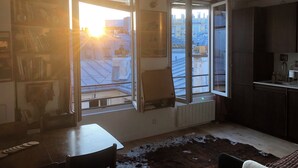 A room with a large window, a radiator, a table, and a cowhide rug. - Vue sur les Toits de Paris ! Calme , Lumineux ! Deux Pièces Refait à Neuf ! (Paris)