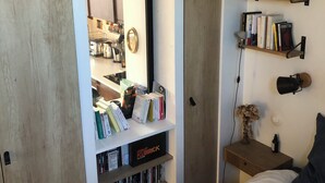 A bedroom with a bed, a bookshelf, and a desk with a lamp. - Vue sur les Toits de Paris ! Calme , Lumineux ! Deux Pièces Refait à Neuf ! (Paris)