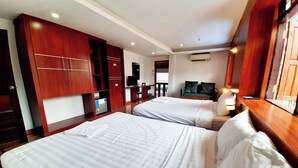 Habitación de hotel con dos camas, armario de madera, escritorio, silla, televisor y aire acondicionado.