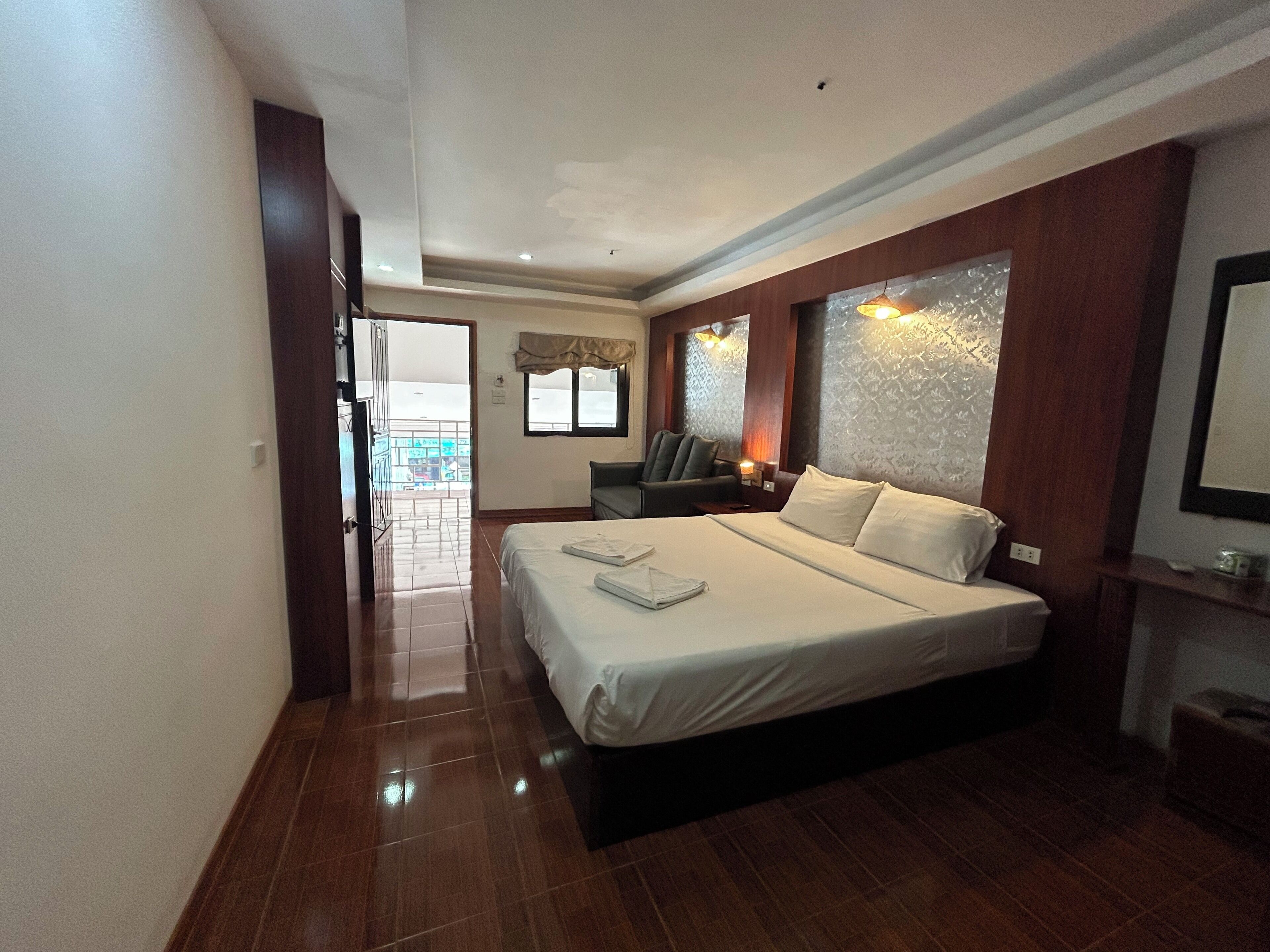 A hotel room with a large bed, a chair, a desk, and a view of the outside.