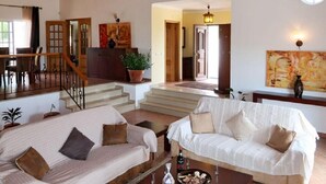 A spacious living room with a sofa, coffee table, and a staircase leading to another level. - Gyrus Villa, São Brás de Alportel, Algarve, Piscina Pool, Wifi (São Brás de Alportel)