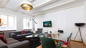 En moderne stue med et glasbord, en grå sofa og en grøn lænestol.