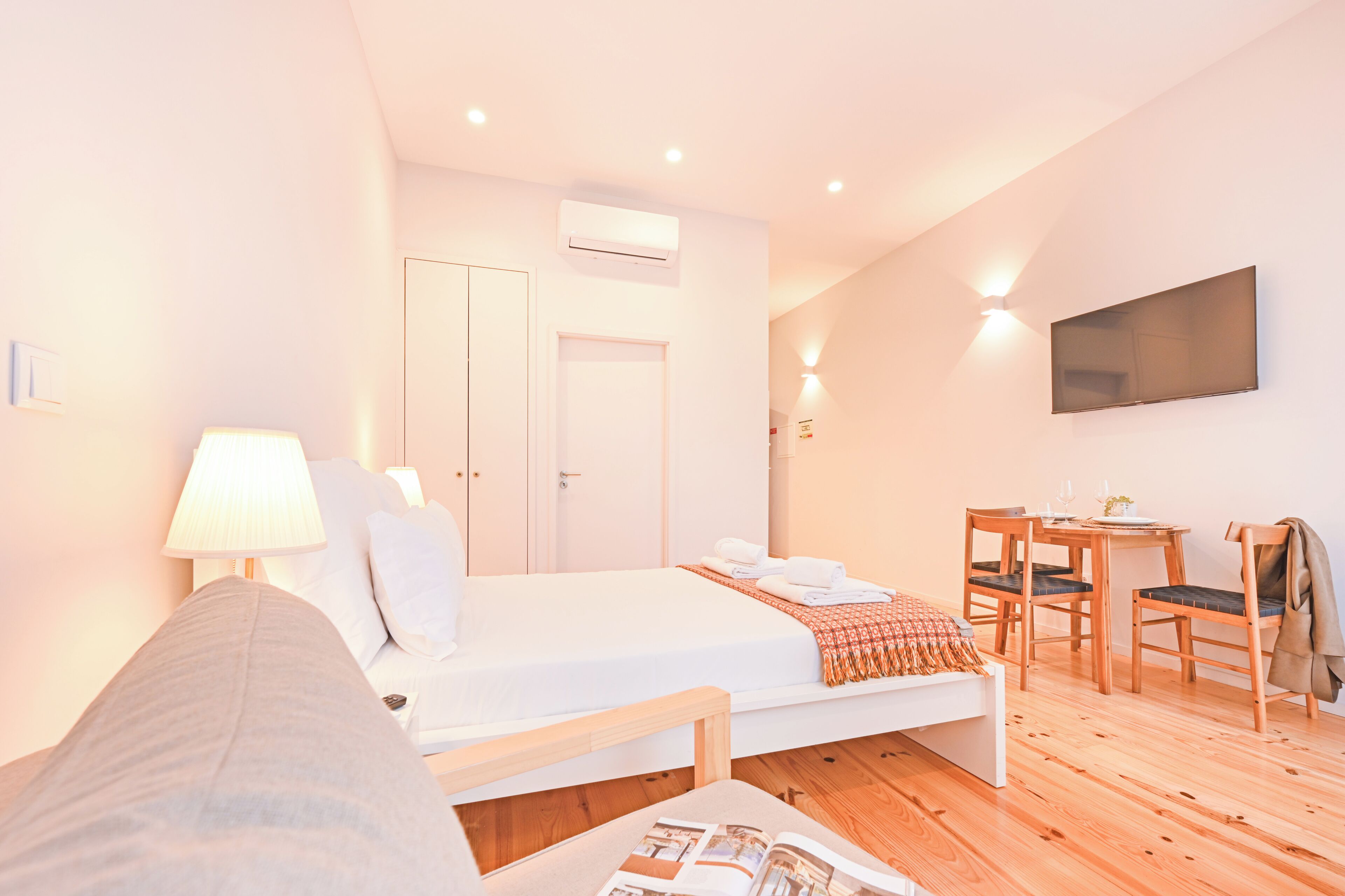 Une chambre d’hôtel équipée d’un lit, d’une table de chevet, d’une lampe et d’un téléviseur fixé au mur.