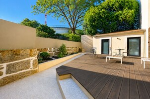 A patio with wooden flooring, stone walls, and a small seating area with tables and chairs.