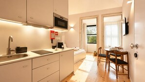 A compact kitchen with a microwave, sink, and a small dining area with a table and chairs. - FindMe inPorto Bonfim (Porto)
