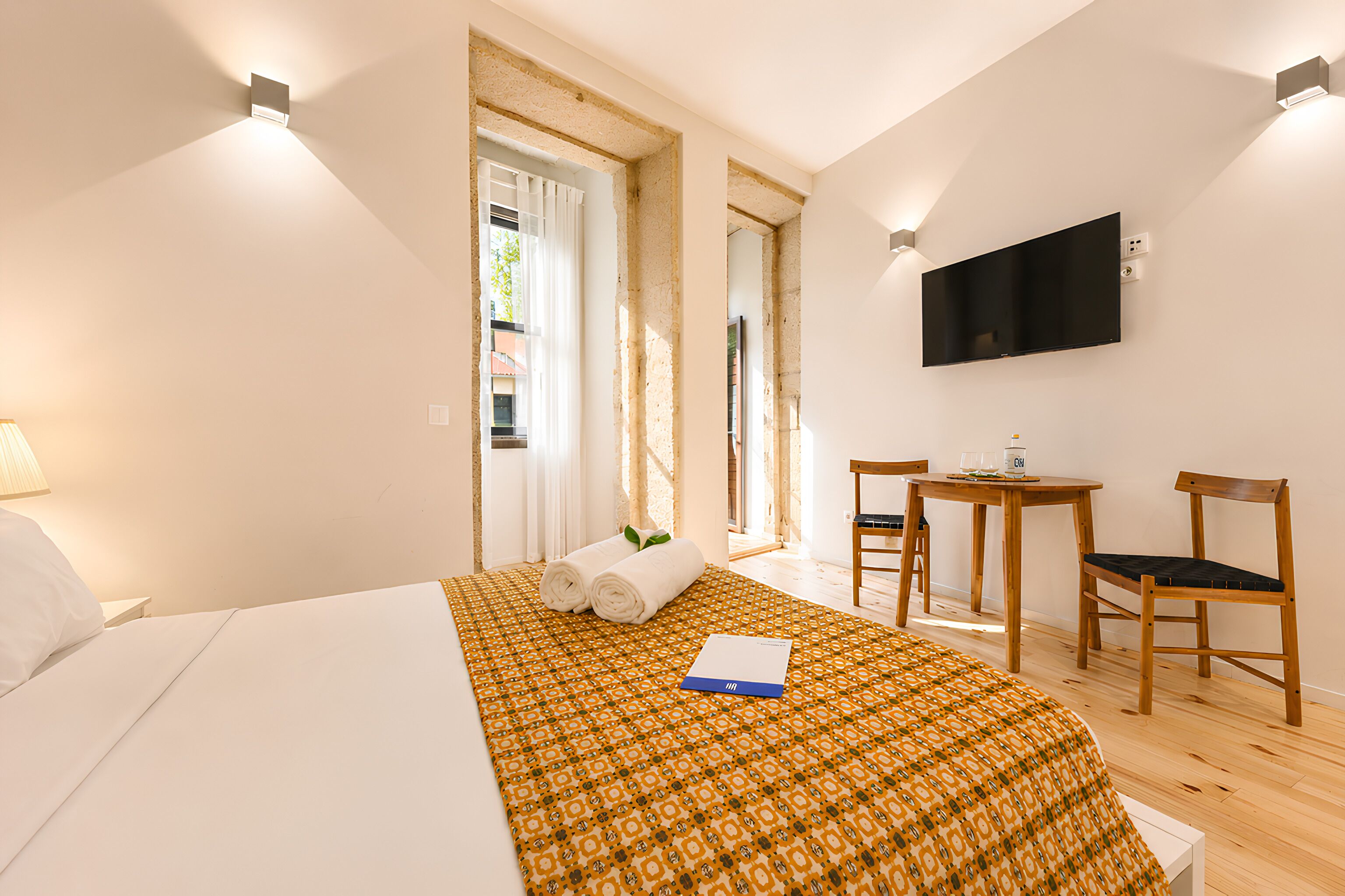 Ett hotellrum med en säng, ett skrivbord, en stol, en tv och ett fönster.