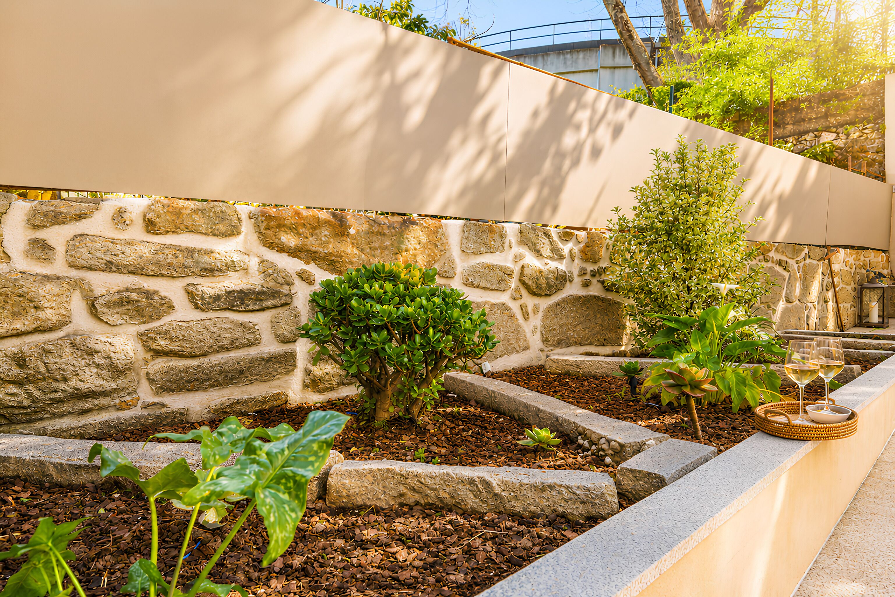 A stone wall with plants and a wicker basket with glasses.