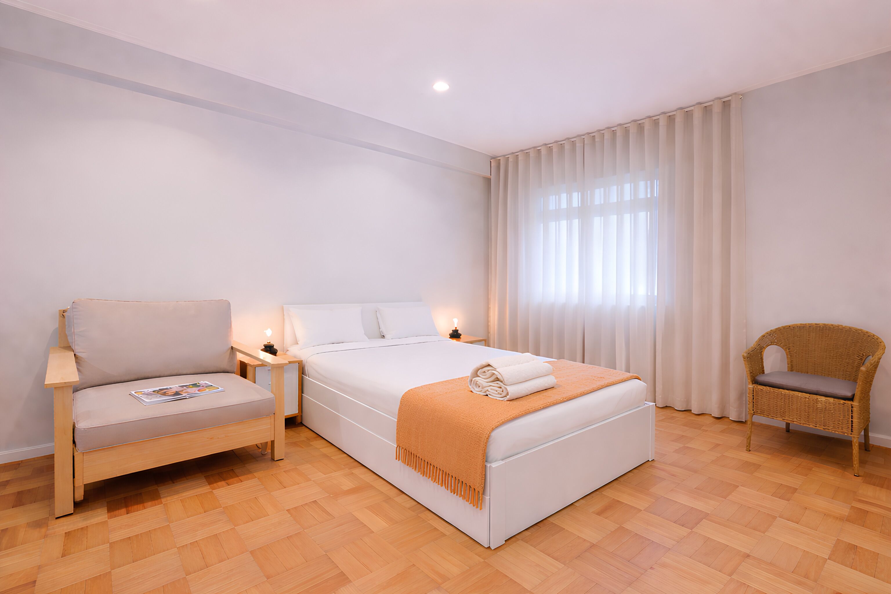 Une chambre à coucher comprenant un lit, un canapé, une chaise, une table de chevet et une fenêtre avec des rideaux.