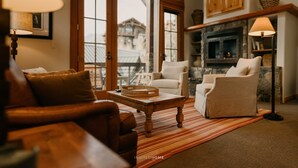 A cozy living room with a fireplace, a large window, and a comfortable seating area.