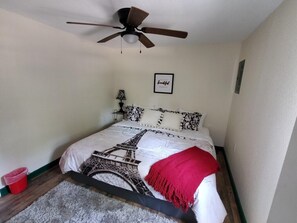 A bedroom with a bed, a ceiling fan, a red bucket, and a framed quote on the wall. - The Juniper ~ Cabin Fourteen ~ Pet Friendly ~ Lakefront (Royal)