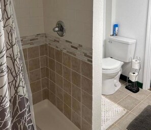 A bathroom with a shower, toilet, and a small rug. - The Juniper ~ Cabin Fourteen ~ Pet Friendly ~ Lakefront (Royal)