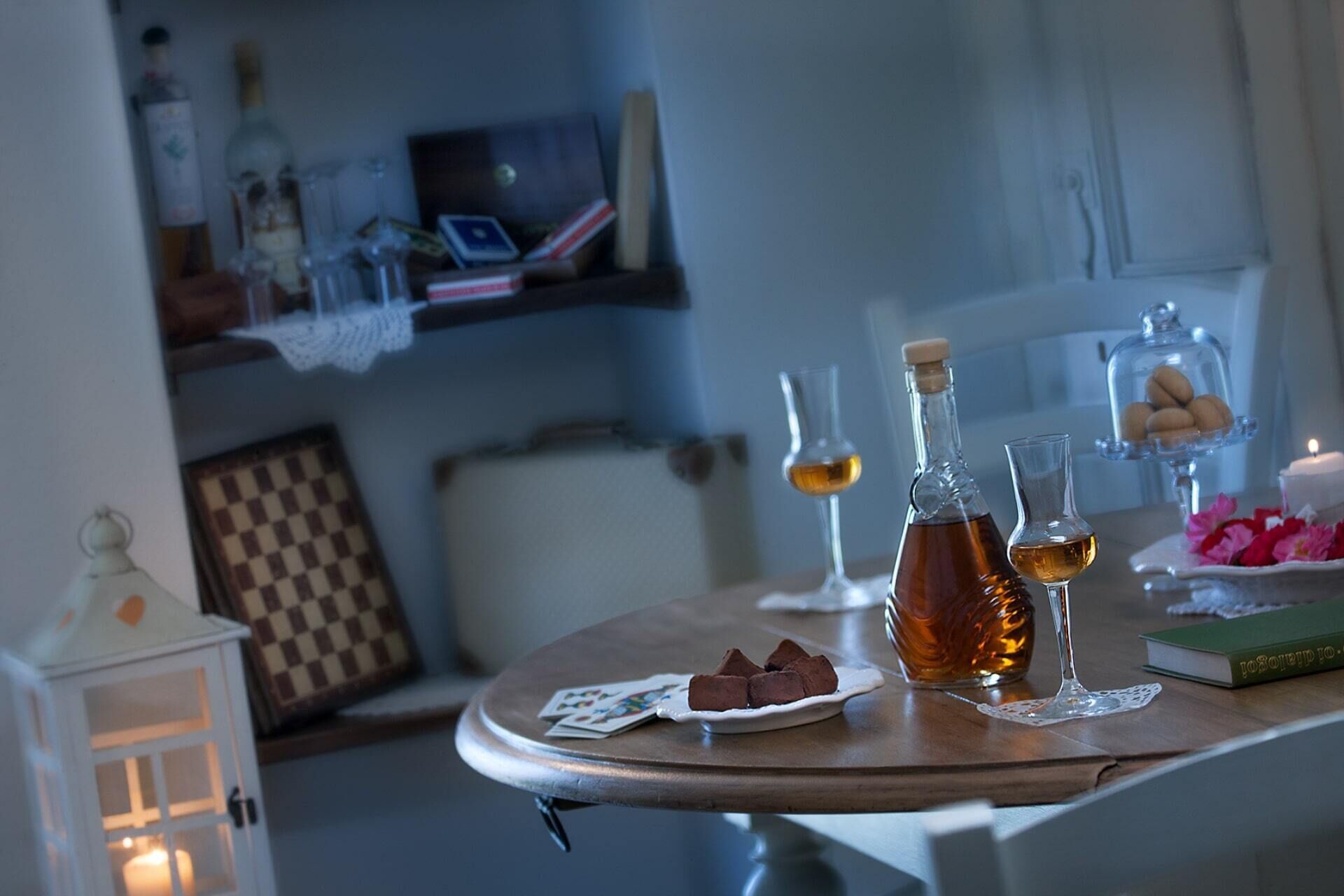 Ein gemütlicher Essbereich mit einem Holztisch, der für eine Mahlzeit gedeckt ist, mit einer Whiskeyflasche, Gläsern und einem Schokoladen Teller.