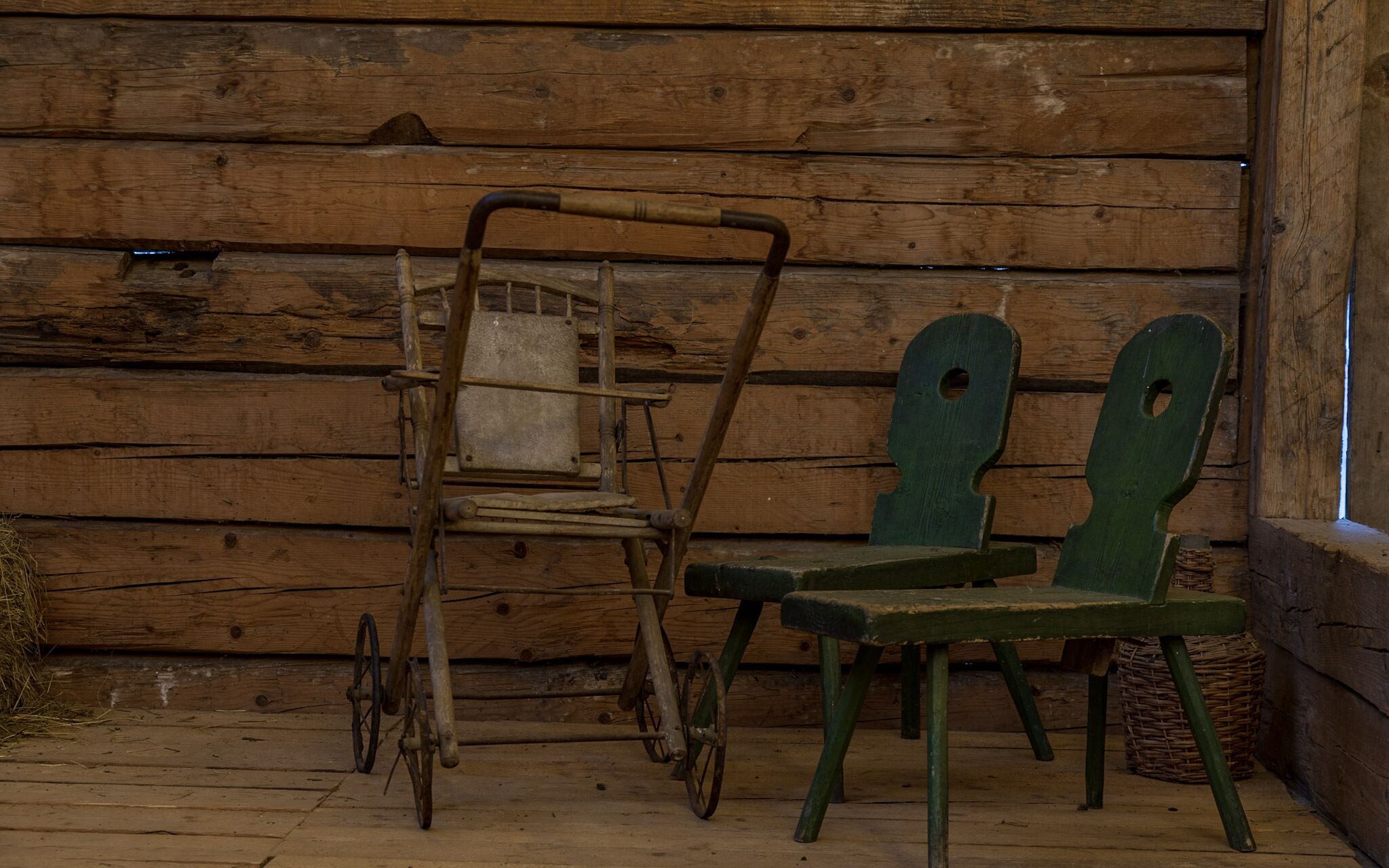 A rustic wooden cabin interior with a wooden chair and a metal folding chair.