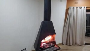 A modern room with a black wood-burning stove, a metal fire screen, and a curtain.