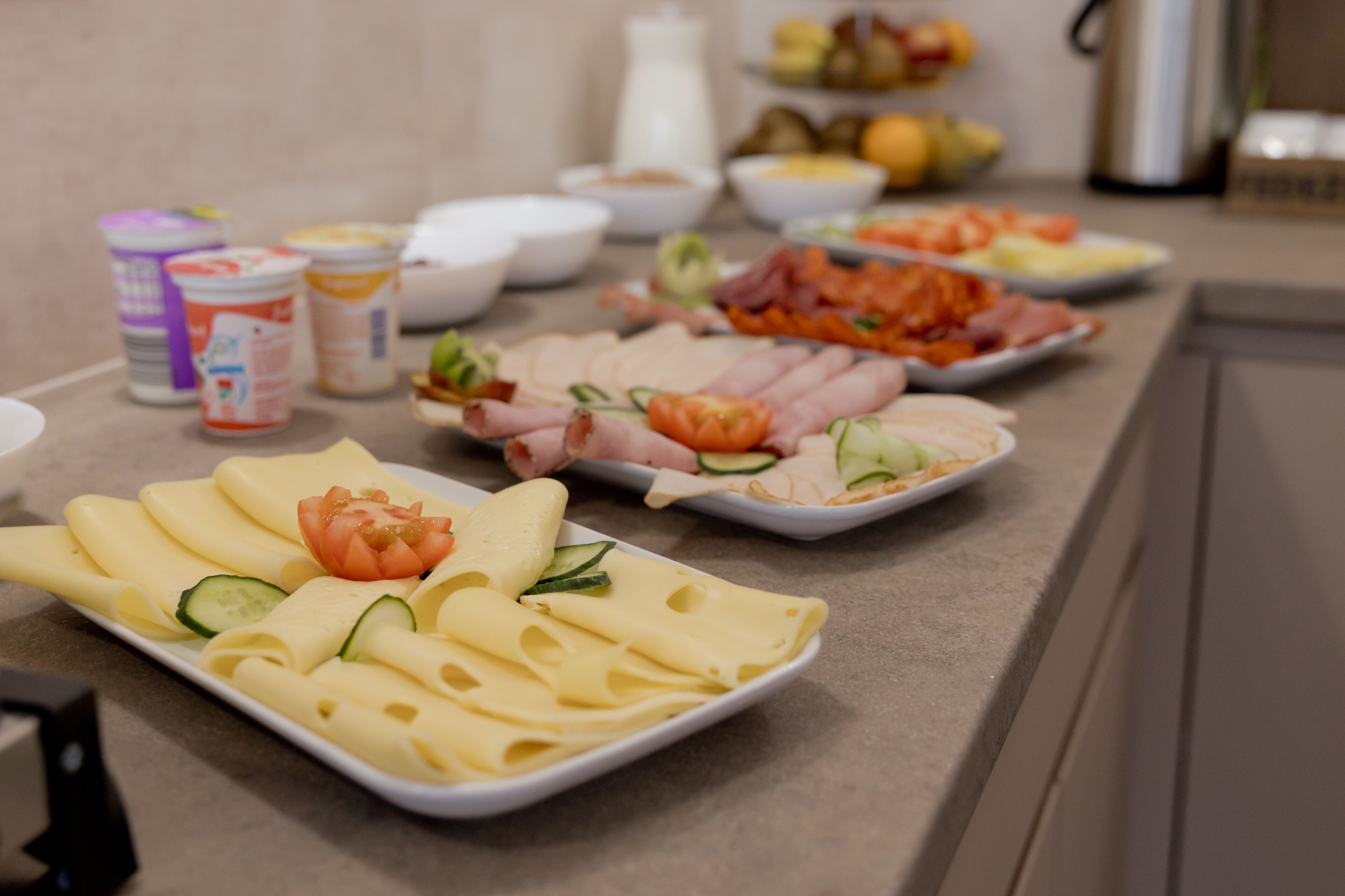 A buffet table with various food items including cheese, ham, and vegetables.