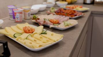 A buffet table with various food items including cheese, ham, and vegetables.