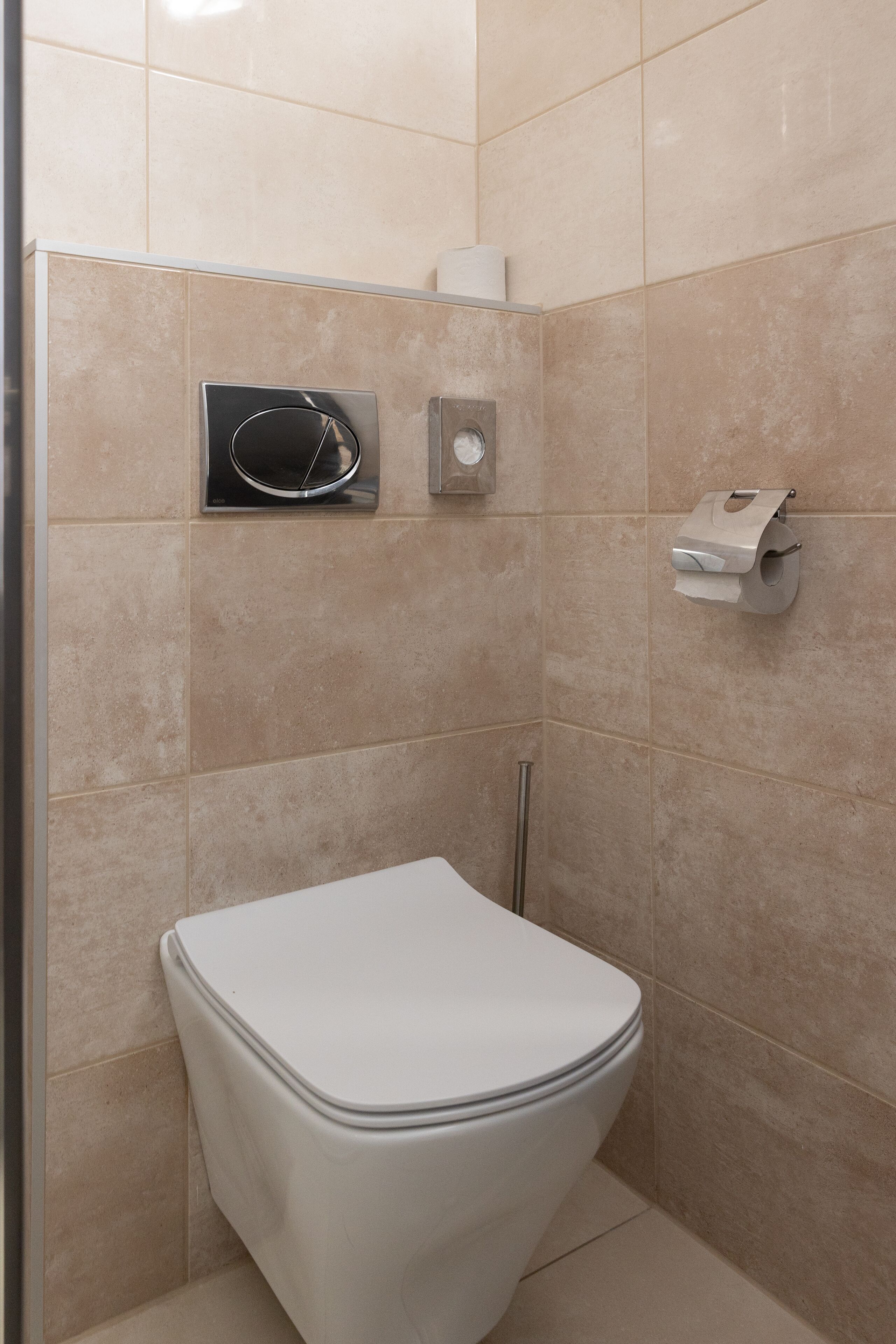 A bathroom with a white toilet, a hand dryer, and a paper towel dispenser.