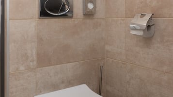 A bathroom with a white toilet, a hand dryer, and a paper towel dispenser.
