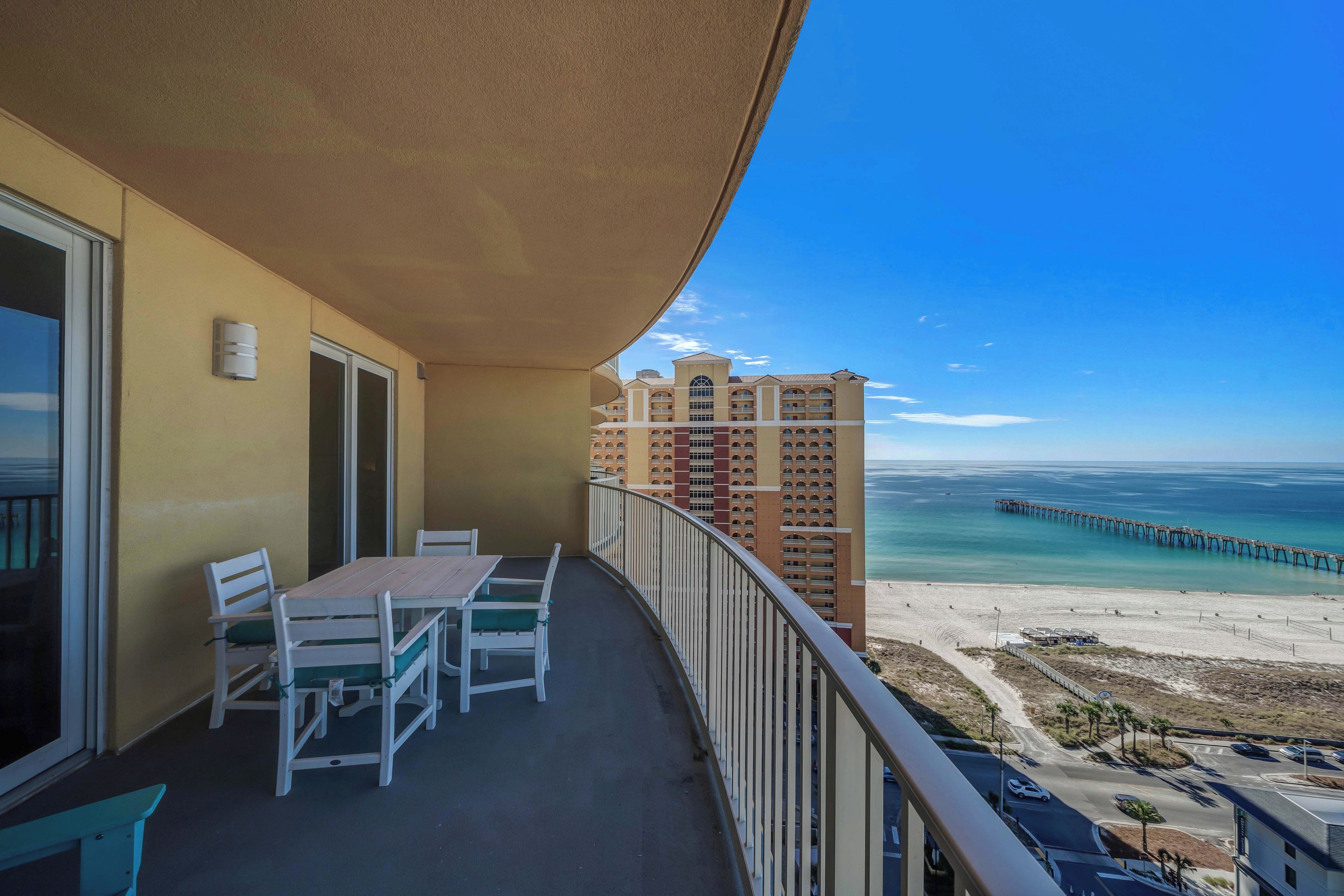 Un balcón con mesa y sillas, con vista a una playa y un muelle.