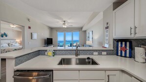 A modern kitchen with a large window, a dishwasher, and a ceiling fan. - Calypso 3-1809 Gulf View King Master, Free Golf&Perks, Pier Park, Heated Pool (Panama City Beach)