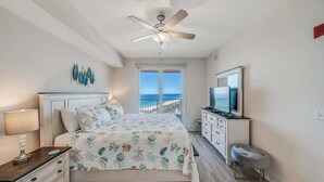 A bedroom with a bed, a nightstand, a dresser, a television, and a ceiling fan. - Calypso 3-1809 Gulf View King Master, Free Golf&Perks, Pier Park, Heated Pool (Panama City Beach)