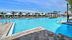 A large outdoor swimming pool with multiple lounge chairs and umbrellas, surrounded by palm trees and covered cabanas. - Calypso 3-1809 Gulf View King Master, Free Golf&Perks, Pier Park, Heated Pool (Panama City Beach)