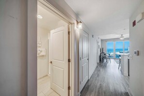 A hallway with a view to a balcony, a dining area, and a ceiling fan.
