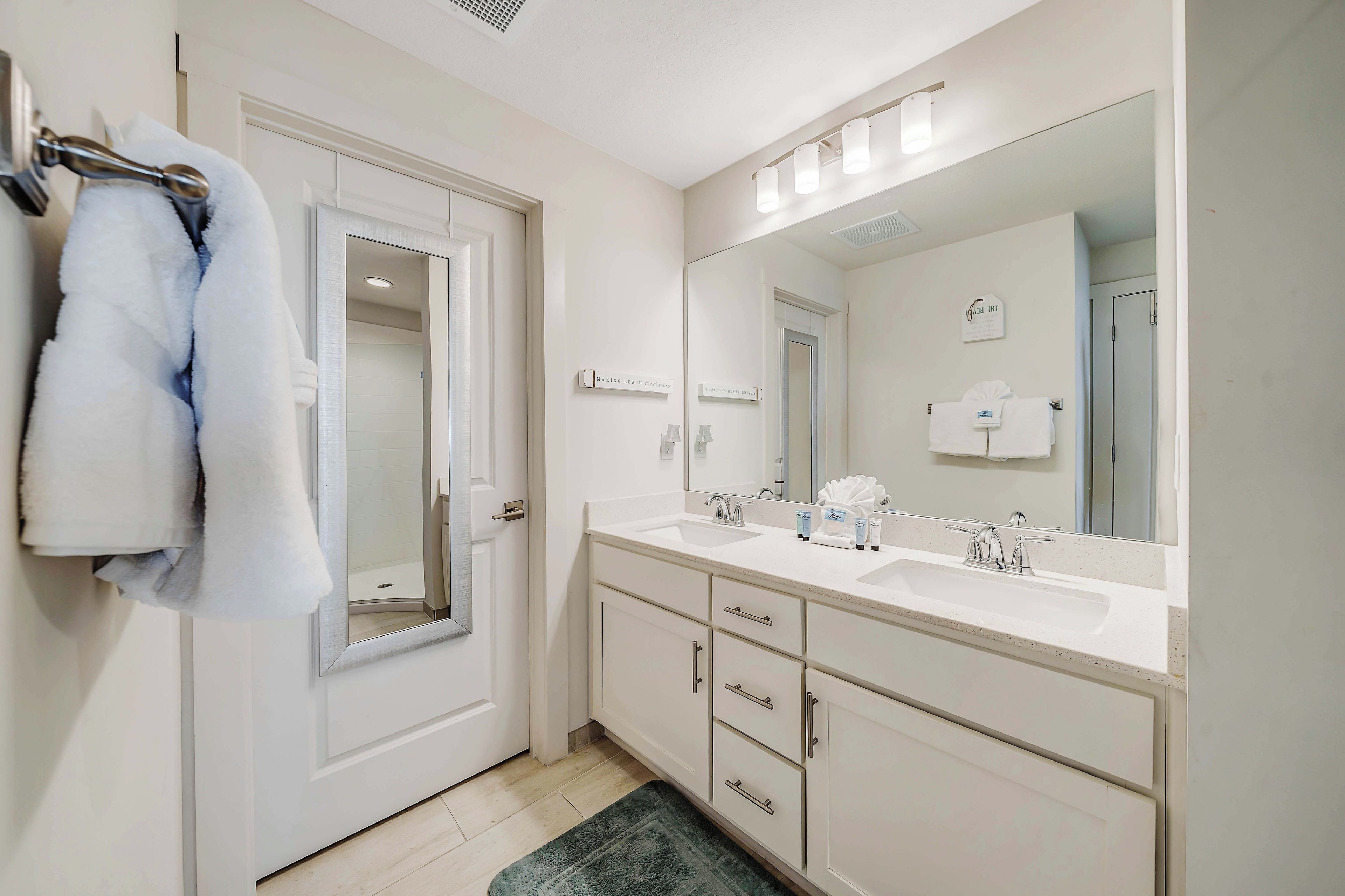A bathroom with a white vanity, a large mirror, and a towel rack.
