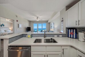 A modern kitchen with a view of the ocean, stainless steel appliances, and a ceiling fan.