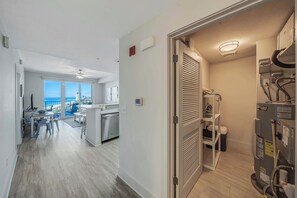 A modern kitchen with a view to the sea, a dining area, and a utility room with a water heater.