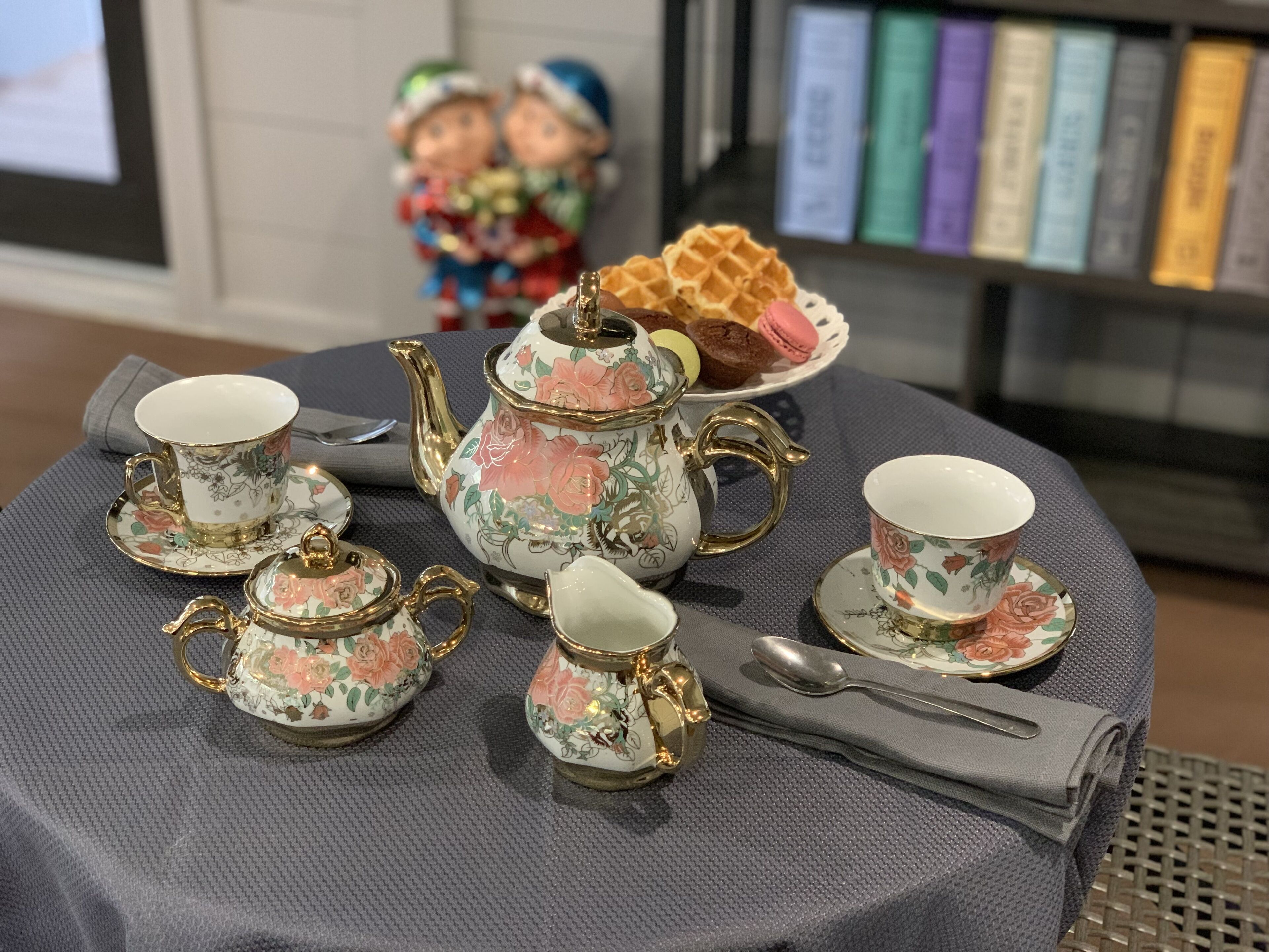 A table set with floral-patterned tea set, including cups, saucers, a teapot, and a sugar bowl.