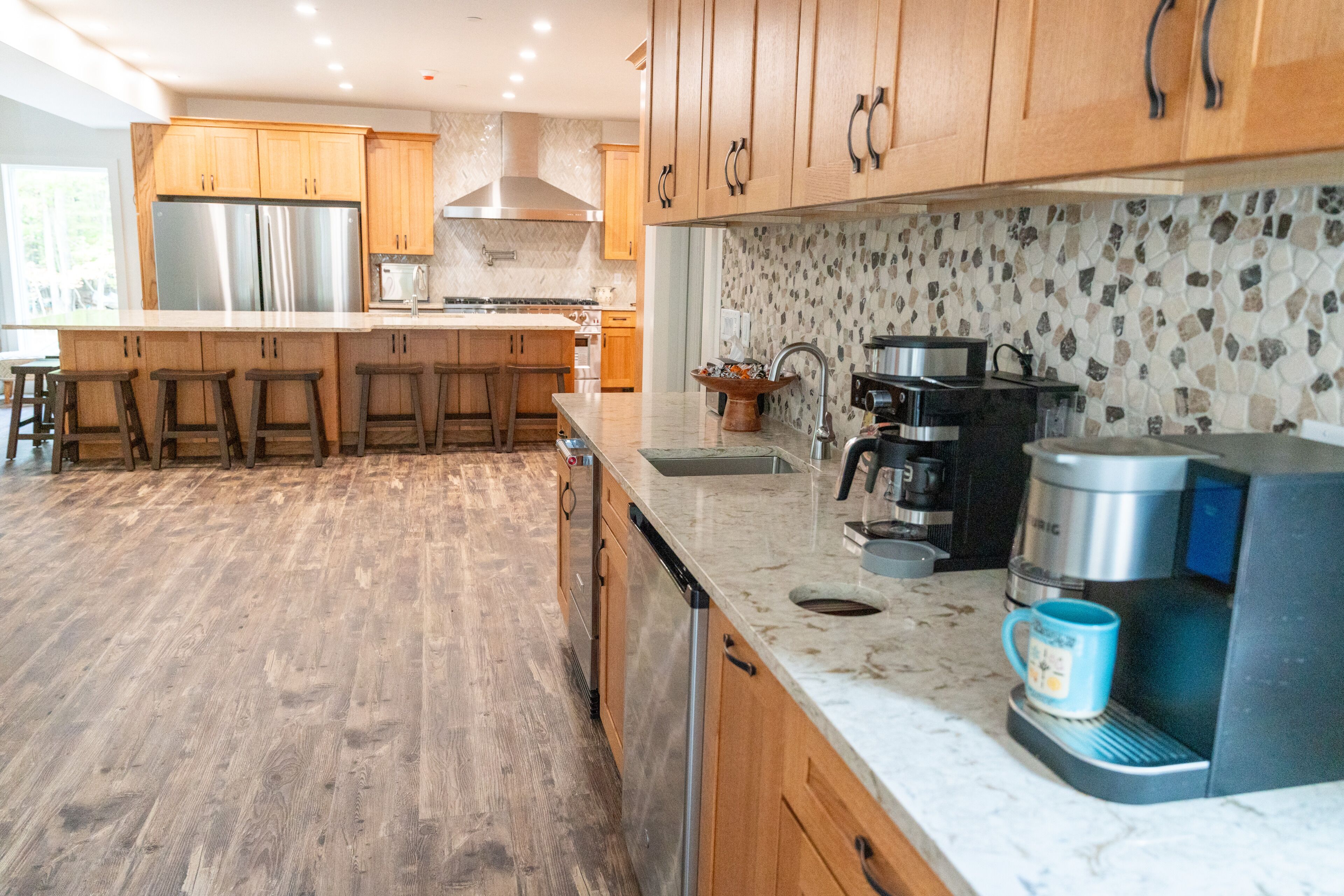 A modern kitchen with wooden cabinets, stainless steel appliances, and a coffee maker.
