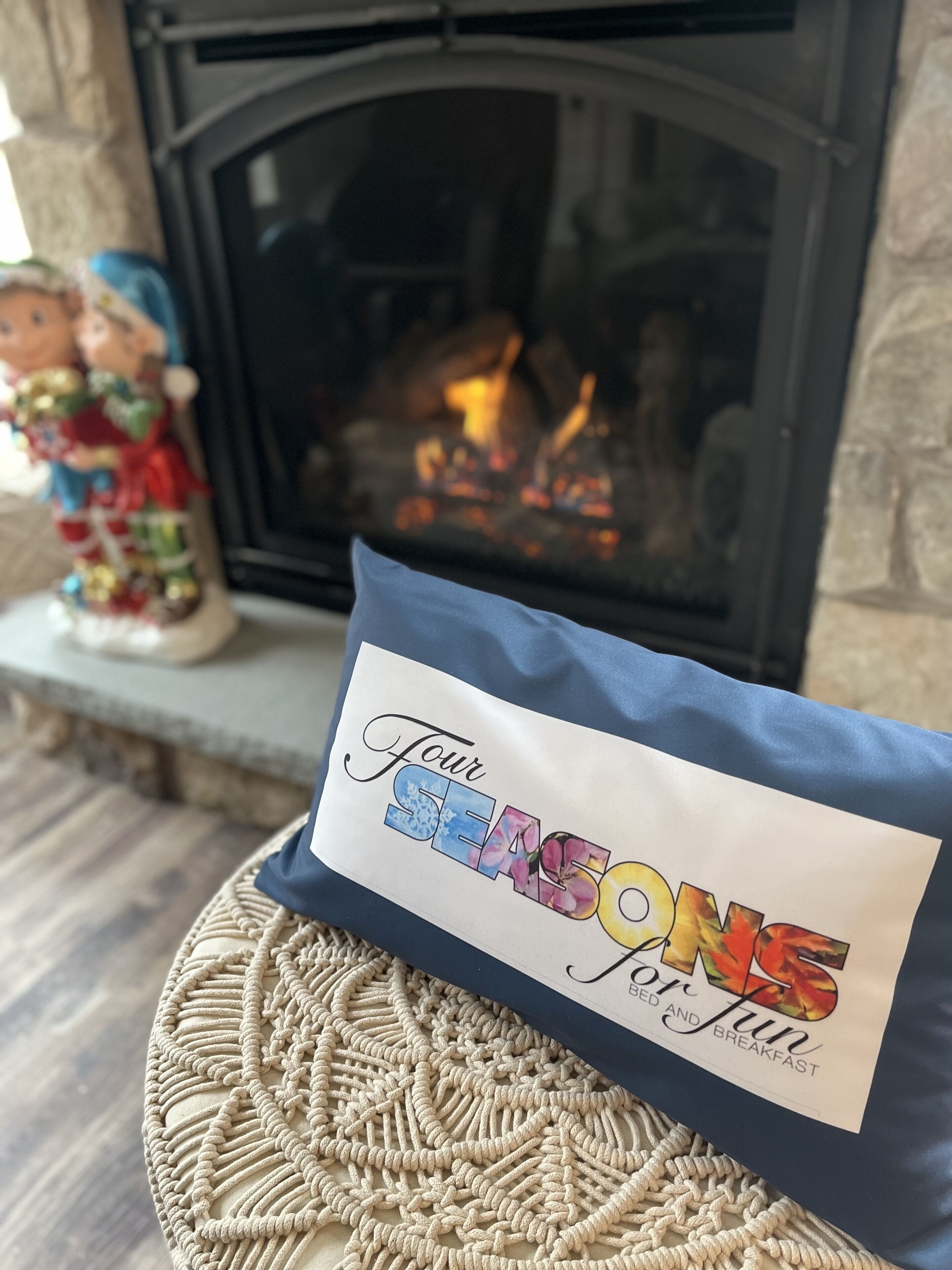 Una habitación acogedora con chimenea, una figurita decorativa y un cojín con la inscripción 'Tour SEASON for fun'.
