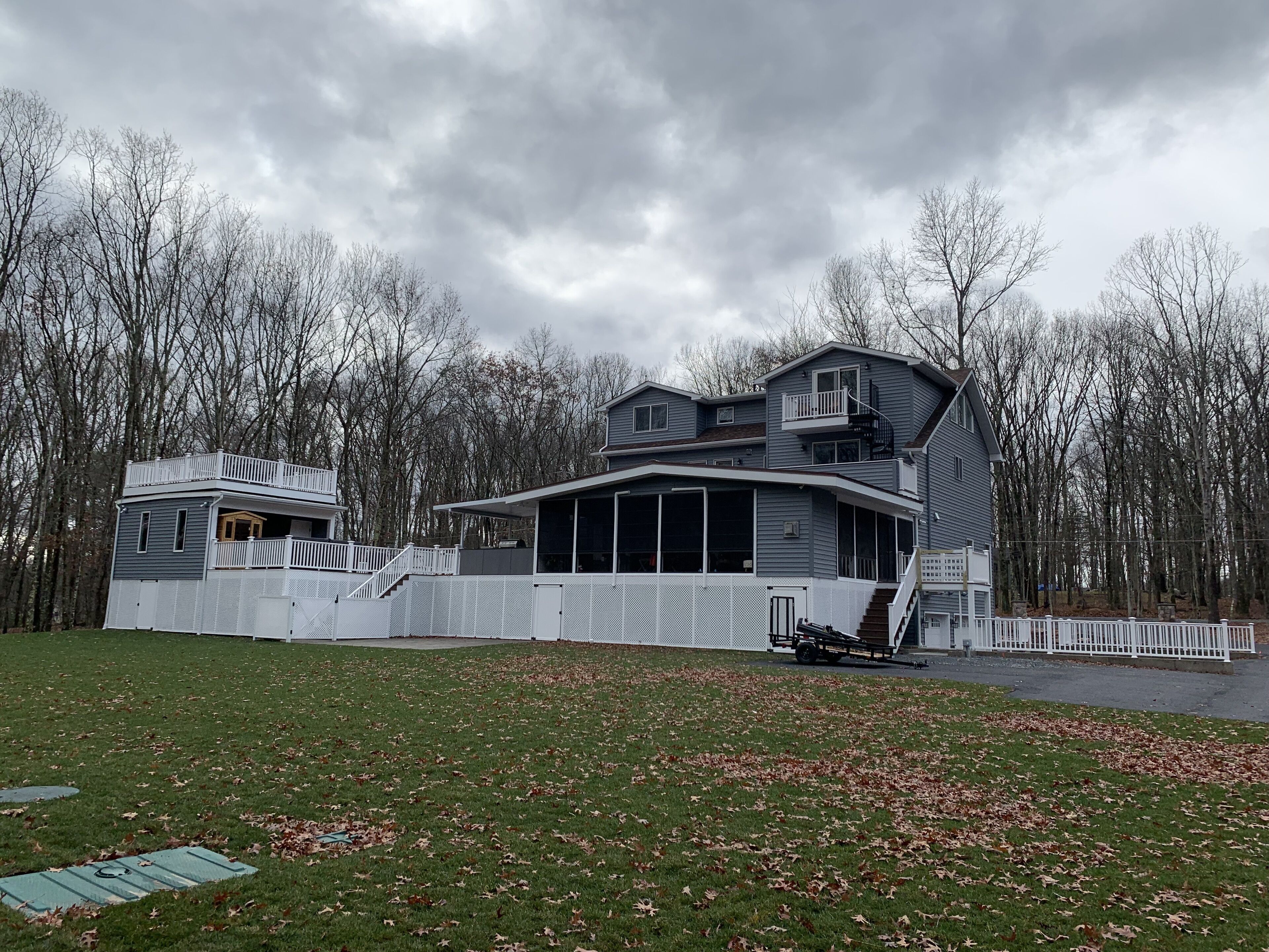 Une maison à deux étages dotée d’une grande terrasse et d’un patio couvert.