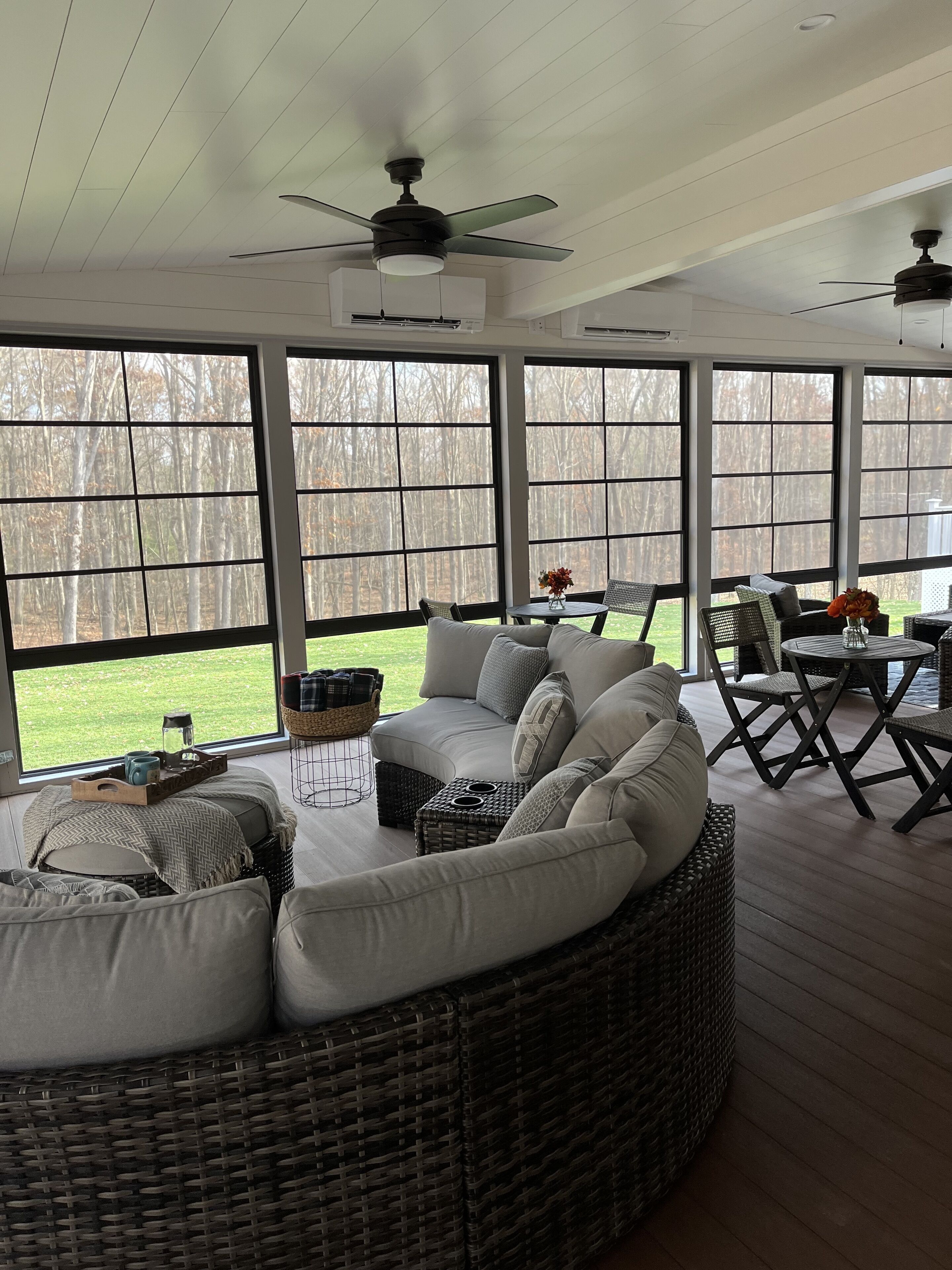 A covered patio area with a large wicker sofa, wicker chairs, and a small table.