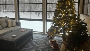 A cozy living room with a large window, a Christmas tree, and a fireplace. - Four Seasons For Fun (Lakeville)