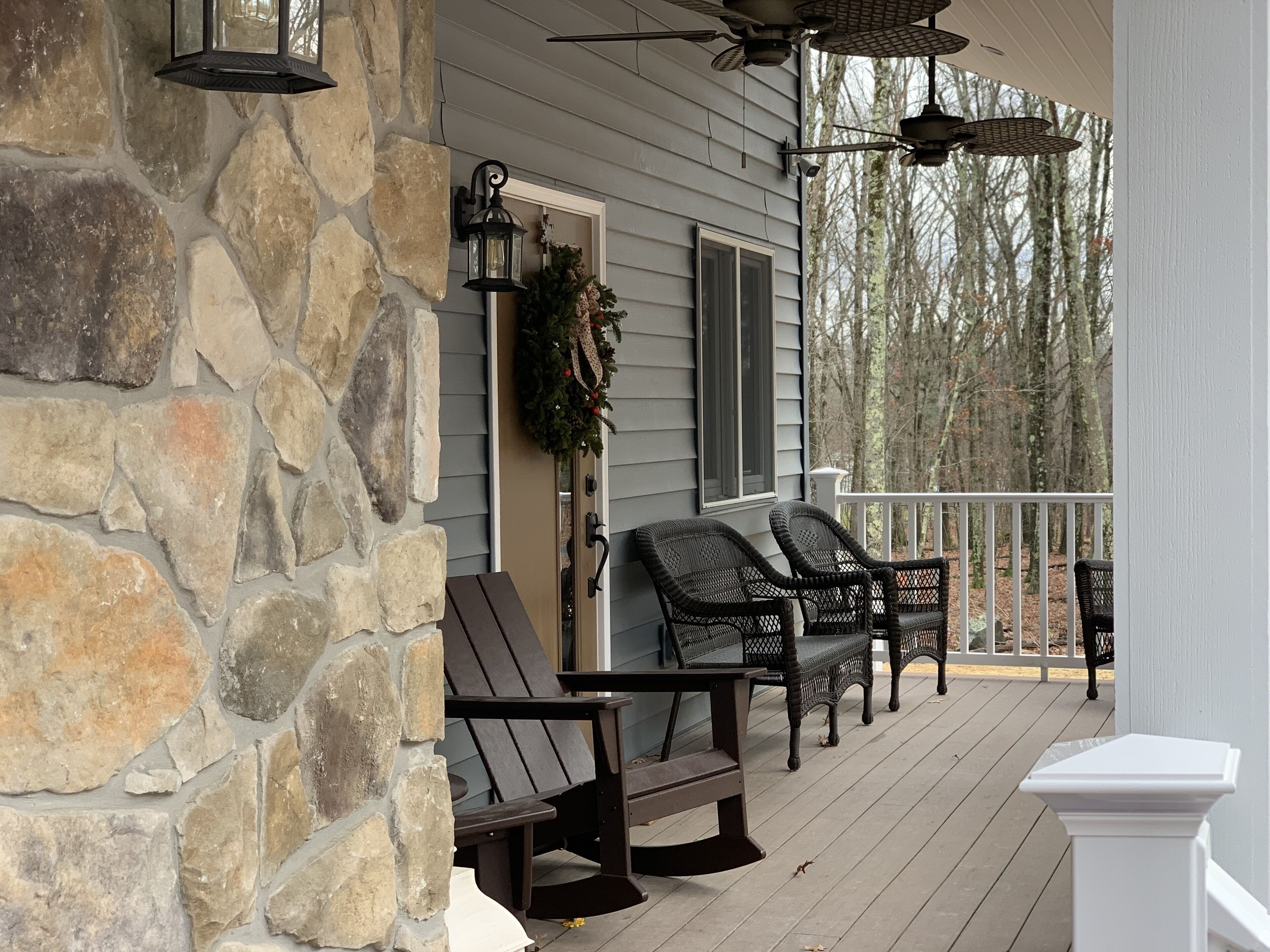 A stone wall, a porch with wicker chairs, and a white column.