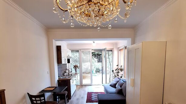 A bedroom with a large bed, a chandelier, a dining area, and a view of the outdoors. - Terrace Suite - KindStay Suites Prague Airport (Stredoceský kraj)