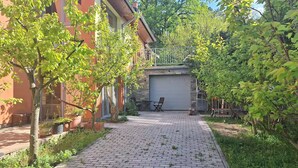 A paved pathway leading to a garage door, flanked by trees and a building with a balcony. - Terrace Suite - KindStay Suites Prague Airport (Stredoceský kraj)