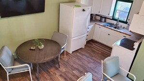 A compact kitchen with white cabinets, a dining table with chairs, and a window with a view.