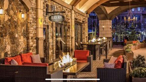 An outdoor seating area with stone walls, a fire feature, and a sign for 'Black Iron Kitchen + Bar'.