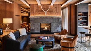A cozy living room with a fireplace, wooden furniture, and a stone accent wall.